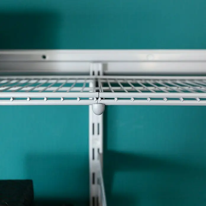 Element System Twin Drahtbodenträger - Länge: 32 cm, Belastbarkeit: 30 kg, Weiß/Aluminium - Nahaufnahme eines weißen, an der Wand montierten Drahtregalsystems mit verstellbaren Schienen und Halterungen für eine individuelle Aufbewahrungslösung.