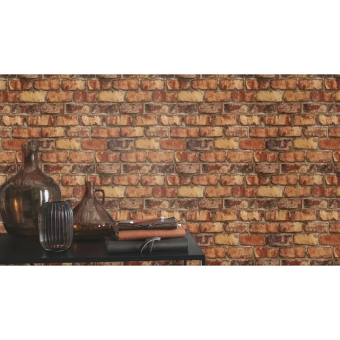 Tesa Rasch Strukturtapete Clayton Backstein - Selbstklebend, Rot/Beige/Orange, Steinoptik, 6 x 0,53 m - Nahaufnahme von dekorativen Glasvasen und Büchern auf einem Tisch vor einer Backsteinmauer, die eine warme und einladende Atmosphäre schaffen.