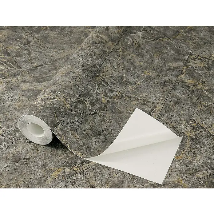 Tesa Rasch Strukturtapete Luxora - Selbstklebend, Grau/Anthrazit, Fliesenoptik, 6 x 0,53 m - Nahaufnahme einer Rolle selbstklebender Marmorfolie. Die Folie zeigt ein dunkles Marmormuster mit goldenen Akzenten und simulierten Fugenlinien.
