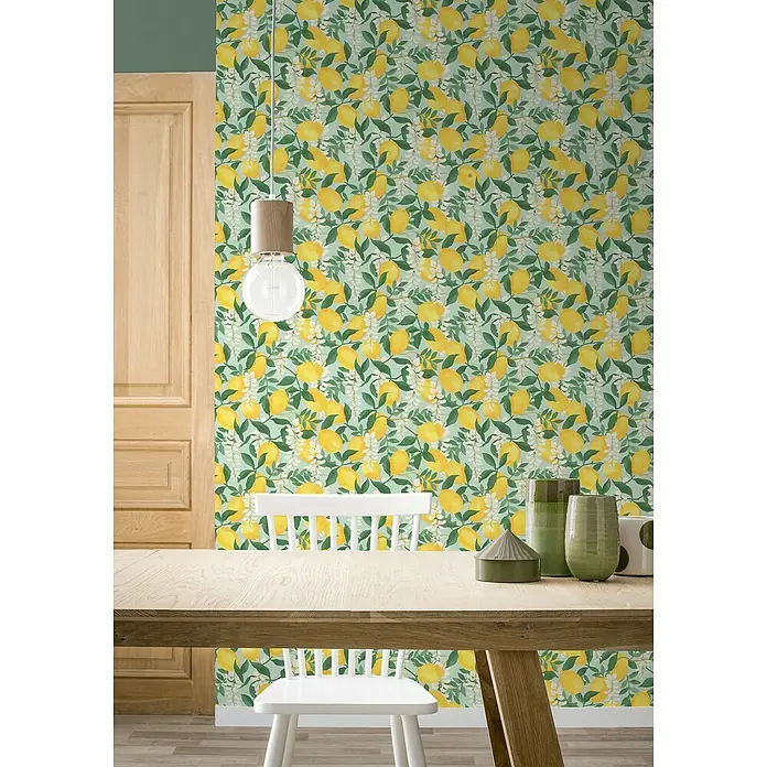 Tesa Rasch Strukturtapete Portofino - Selbstklebend, Blau/Grün/Gelb, Floral, 6 x 0,53 m - Ein Esstisch mit einem weißen Stuhl und dekorativen Vasen, vor einer Wand mit Zitronenmuster-Tapete und einer hölzernen Tür.
