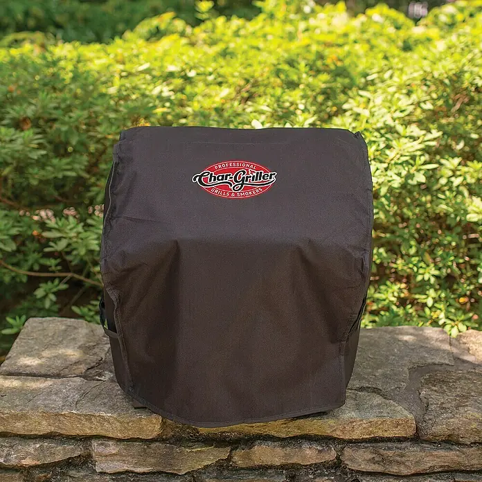 Char-Griller Grill-Schutzhülle - Passend für: Char-Griller Portable Grill Modelle 22424, 72424, E82424 und 924240 - Dunkelgraue Char-Griller Grillabdeckung mit Logo, die einen Grill auf einer Steinmauer bedeckt.