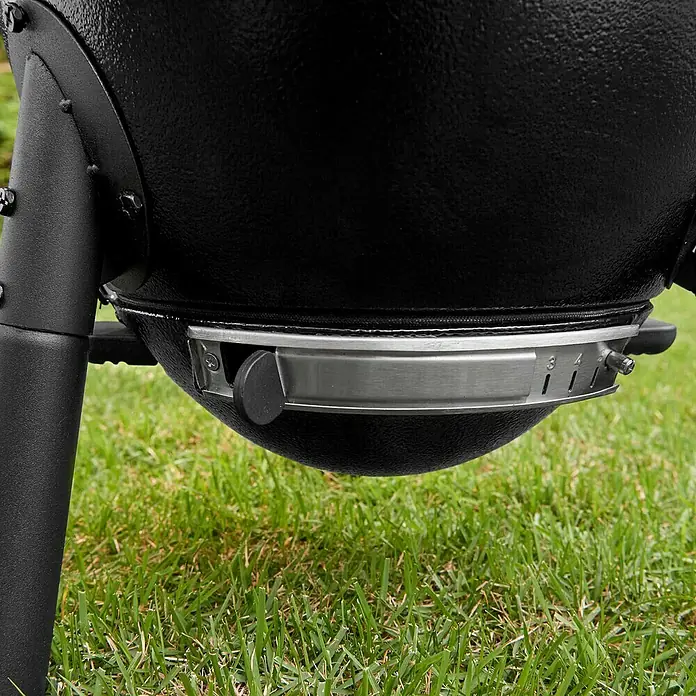 Char-Griller Holzkohlegrill Akorn Jr. Kamado - Durchmesser Grillfläche: 36 cm, Schwarz - Schwarzer, texturierter Grillboden mit metallischem Lüftungsschieberring, der nummerierte Einstellungen und ein Bein zeigt.