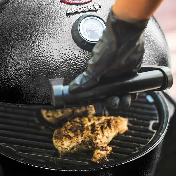 Char-Griller Holzkohlegrill Akorn Jr. Kamado - Durchmesser Grillfläche: 36 cm, Schwarz - Person mit schwarzem Handschuh bedient schwarzen, strukturierten Akorn Grill mit Hähnchen.