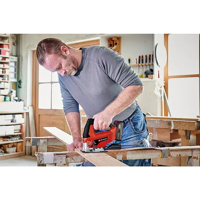 Einhell Power X-Change 18V Maschinen-Set - 18 V, 2 Akkus, 3 Ah, 10 -tlg. - Ein Mann arbeitet mit einer Einhell Akku-Stichsäge, um präzise Holzschnitte durchzuführen. Das Werkzeug ermöglicht flexibles und kabelloses Arbeiten in der Werkstatt.