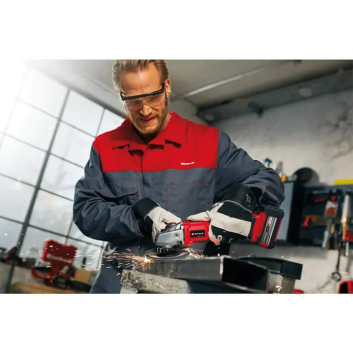 Einhell Power X-Change 18V Maschinen-Set - 18 V, 2 Akkus, 3 Ah, 10 -tlg. - Ein Mann benutzt einen Einhell Akku-Winkelschleifer, um Metall zu schleifen, wobei Funken fliegen. Er trägt Schutzkleidung für die Arbeitssicherheit.