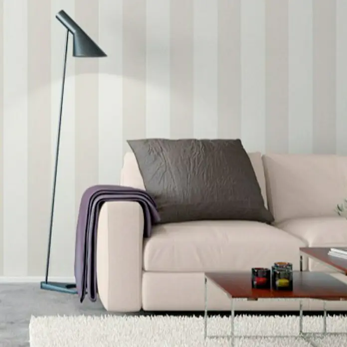 Papel pintado Básico de rayas - Beige/Crema, Rayas, 10 x 0,53 m - Elegante lámpara de pie negra junto a un sofá crema con cojín gris y manta morada.