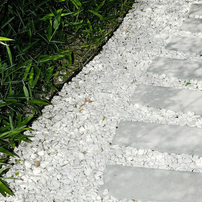 Piedras decorativas 20/40 Big Bag - Blanco, 1.000 kg - Grava decorativa blanca entre plantas verdes y losas de piedra gris como elemento decorativo de jardín.