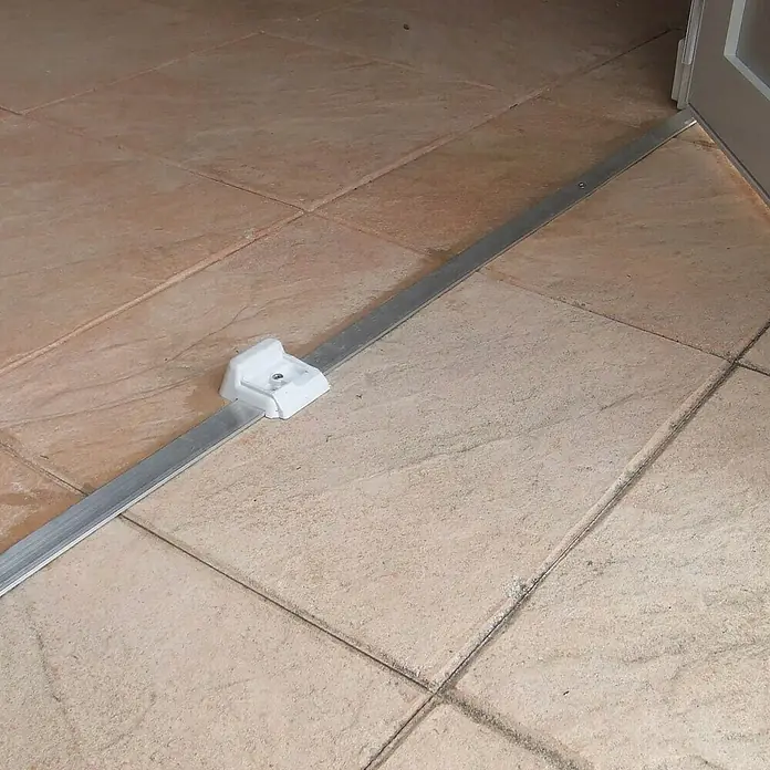 Grosfillex Caseta para jardín Deco - Medidas ext. (An x Pr): 370 x 298 cm, Plástico, Beige/Blanco, 7,5 m² - Carril metálico plateado con guía de plástico blanco instalado en un suelo de baldosas.