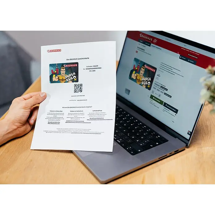 Gutscheinkarte - Zum Selbstausdruck, Individueller Betrag, Super Hero Vatertag - Bauhaus-Gutscheinkarte „Super Hero“ mit 60 € Guthaben, präsentiert auf einem Laptop. Ideal zum Verschenken und Online-Einlösen im Shop.
