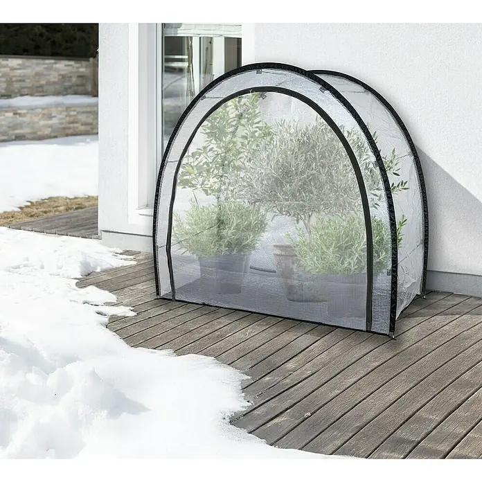 Windhager Winterschutzzelt Qinog - 80 x 180 x 170 cm, Gitterfolie - Nahaufnahme eines Gewächshauses mit Pflanzen auf einer Holzterrasse im Schnee.