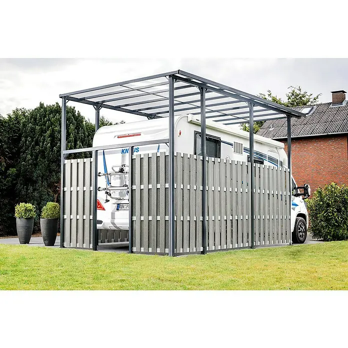 DWS Outdoor Carport Premium XL - Außenmaß inkl. Dachüberstand (B x T): 3,31 x 5,41 m, Anthrazit, Carport geeignet für: Caravans - Graues Metall-Carport mit lichtdurchlässigem Dach und grauen Lamellen-Seitenwänden, schützt einen weißen Camper auf einem gepflasterten Bereich neben Rasen.