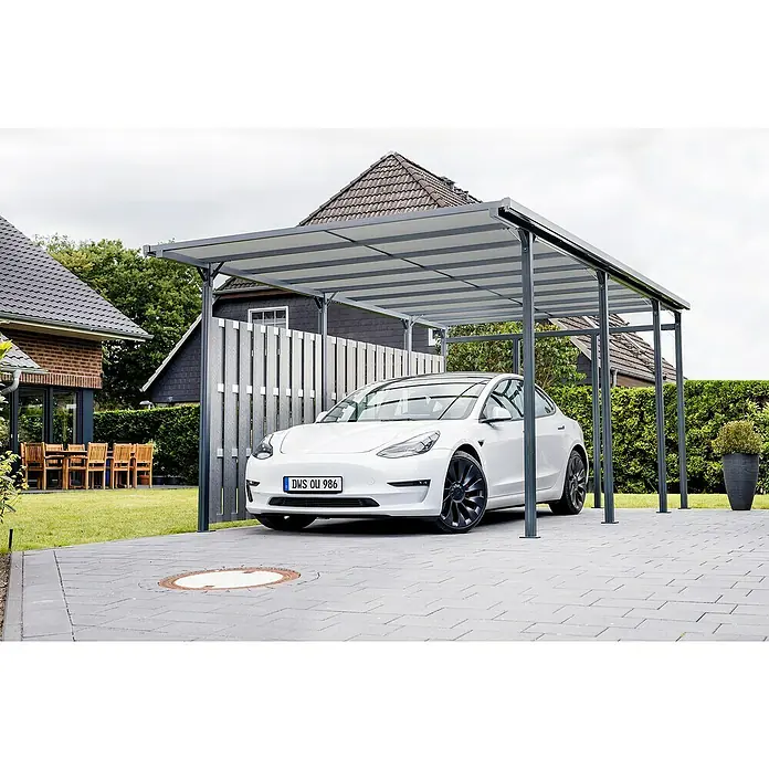 DWS Outdoor Carport Premium L - Außenmaß inkl. Dachüberstand (B x T): 3,31 x 5,41 m, Anthrazit, Carport geeignet für: PKWs - Graues Metall-Carport mit durchscheinenden Dachpaneelen, das einen weißen Tesla Model 3 auf einer gepflasterten Auffahrt schützt.