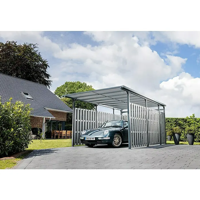 DWS Outdoor Carport Premium L - Außenmaß inkl. Dachüberstand (B x T): 3,31 x 5,41 m, Anthrazit, Carport geeignet für: PKWs - Ein grauer Carport mit lichtdurchlässigem Dach und Lamellen-Seitenwänden schützt ein dunkelgrünes Auto auf einer Einfahrt neben einem Haus.