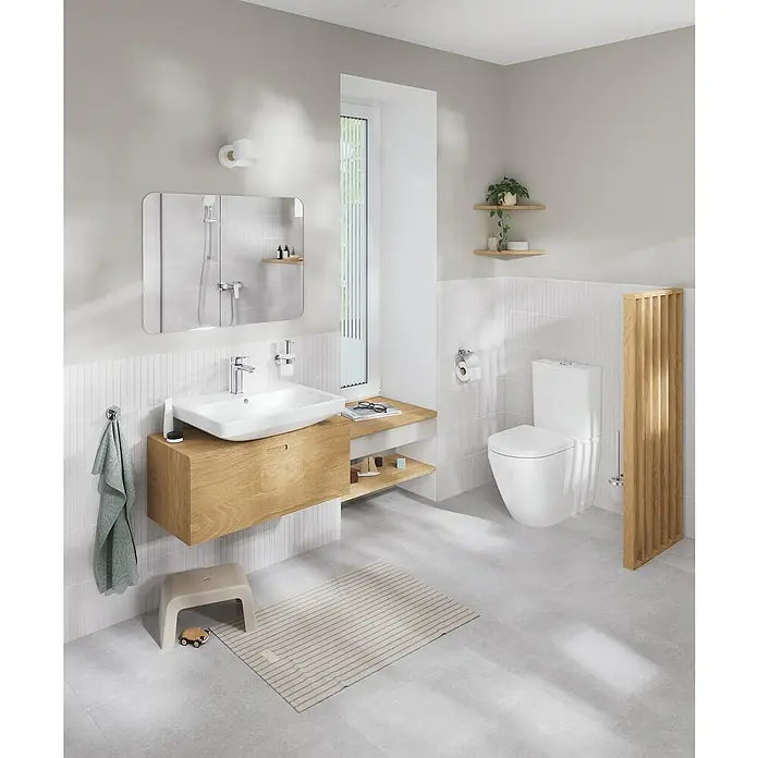 Grohe QuickFix Start Toilettenpapierhalter - Chrom - Ein modernes Badezimmer mit einem wandmontierten Waschtisch aus hellem Holz, einer Toilette und einem Spiegel. Die Einrichtung ist minimalistisch und hell gestaltet.