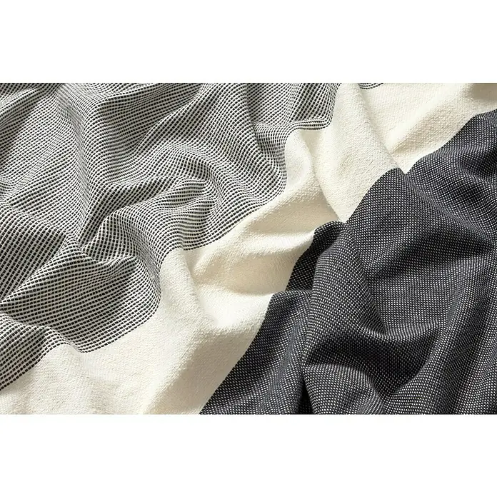 Manta para sofá Vigore Rayas - Textil, Antracita - Primer plano de una manta de algodón plegada con un patrón de rayas en tonos grises, blancos y antracita, resaltando la textura y el confort.