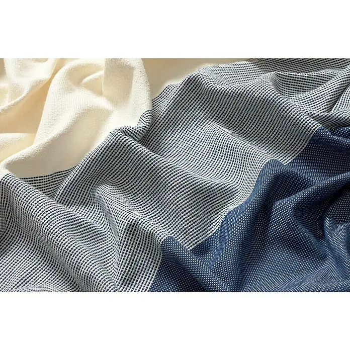 Manta para sofá Raya Centro - Textil, Marino - Primer plano de una manta de algodón tricolor plegada con una textura tejida en beige, blanco y azul marino.