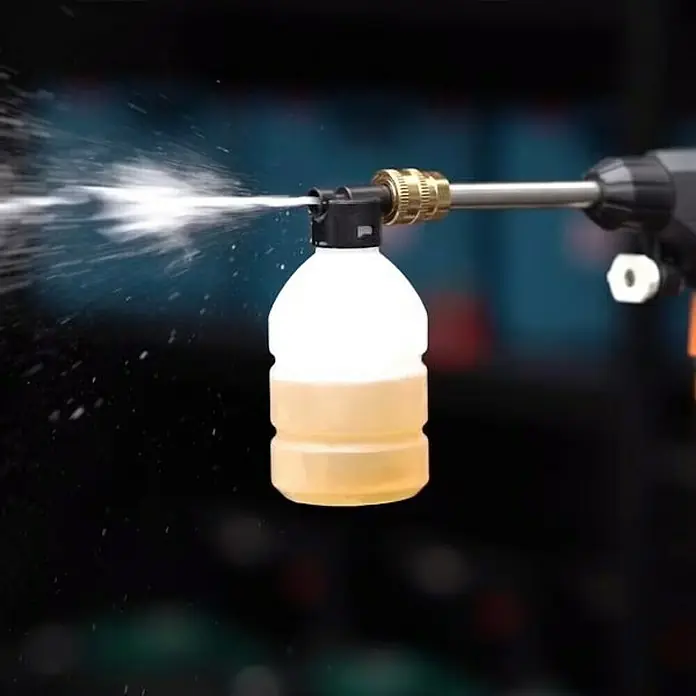 Hidrolimpiadora de alta presión de batería Hydroblast - 9,5 bar, 21 V, Capacidad de bombeo: 210 l/h - Primer plano de una botella de spray conectada a una pistola de lavado de coches, rociando agua.
