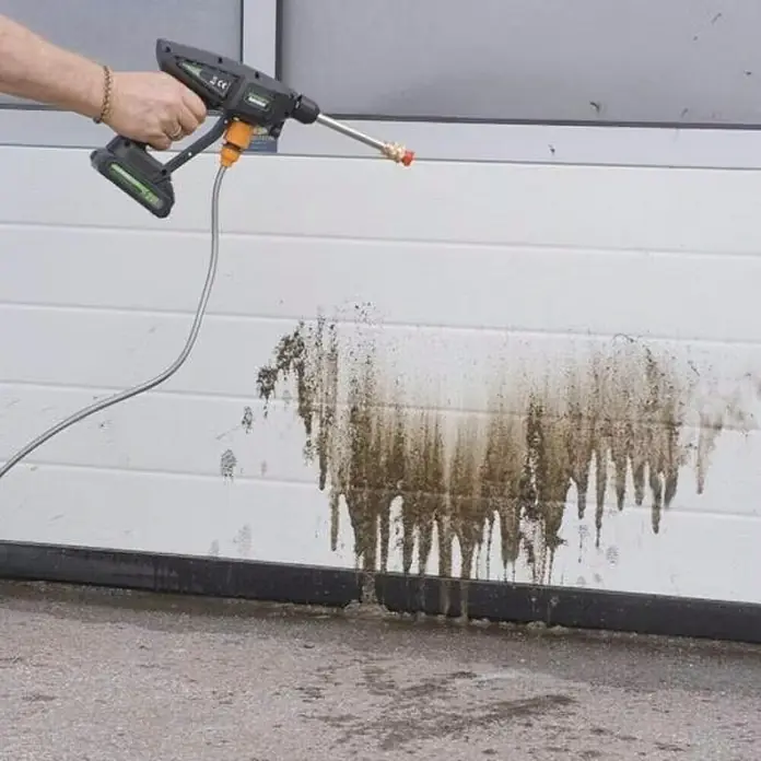 Hidrolimpiadora de alta presión de batería Hydroblast - 9,5 bar, 21 V, Capacidad de bombeo: 210 l/h - Hidrolimpiadora portátil a batería en acción, eliminando la suciedad de una superficie blanca.