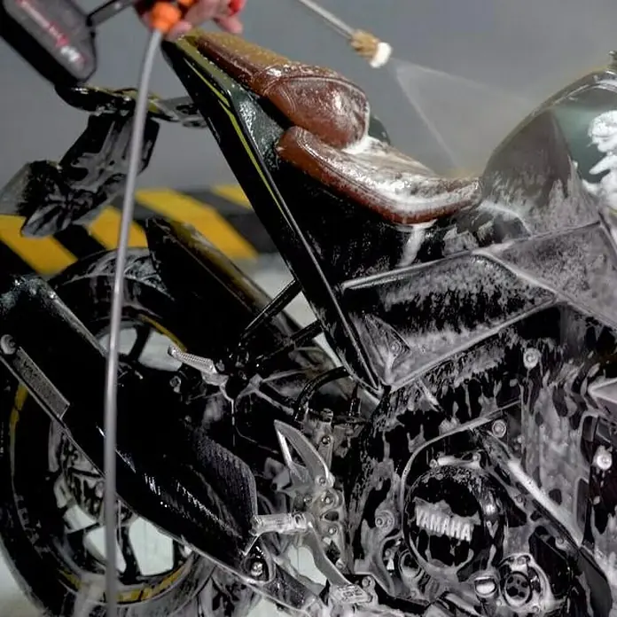 Hidrolimpiadora de alta presión de batería Hydroblast - 9,5 bar, 21 V, Capacidad de bombeo: 210 l/h - Primer plano de una motocicleta cubierta de espuma que se limpia con agua. La atención se centra en la limpieza del vehículo.