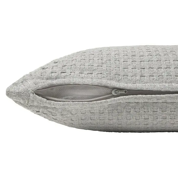 Cojín Waffle - 40 x 60 cm, Textil, Gris, Rectangular - Primer plano de un cojín gris claro con textura de gofre y cremallera visible. Ideal para decoración de salón o dormitorio.