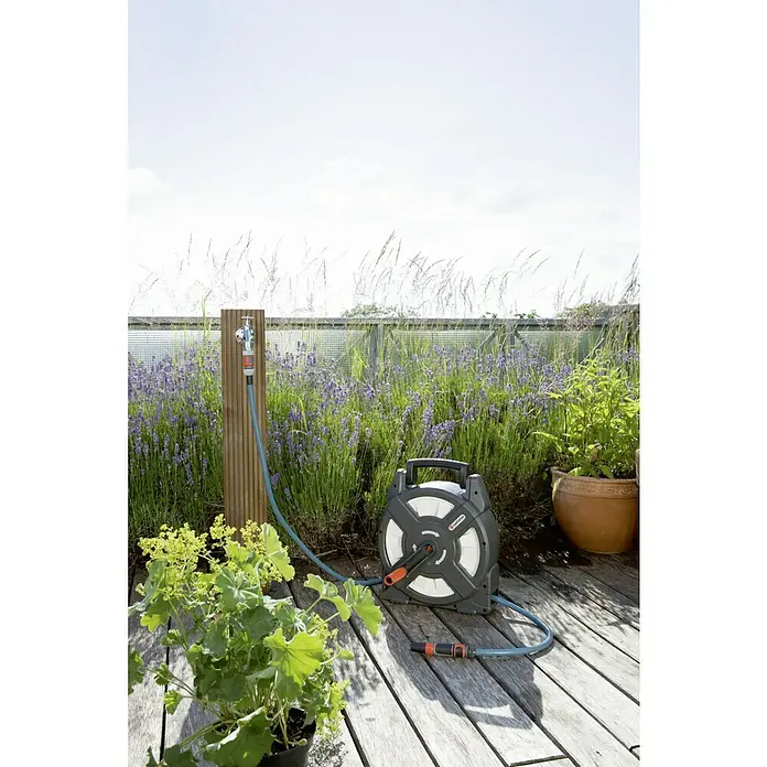 Gardena Schlauchtrommel - Schlauchlänge: 10 m, Kunststoff - Gartenschlauchaufroller von Gardena mit Schlauch und Anschlussstück vor einer üppigen Gartenkulisse.