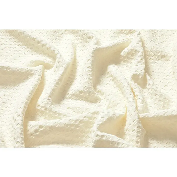 Manta para sofá Multiusos Waffle - Textil, Natural - Primer plano de un tejido waffle arrugado color crema que muestra textura y pliegues suaves. Ideal para proyectos textiles o fondos texturizados.