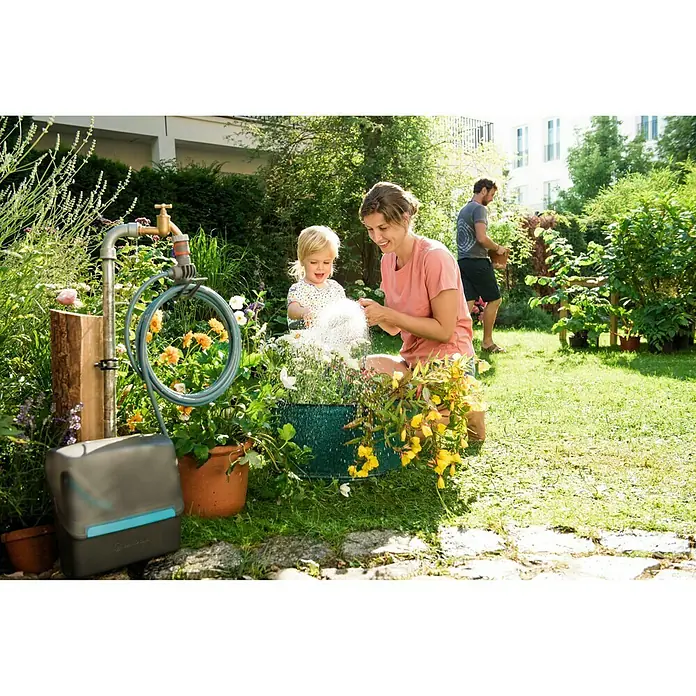 Kit de manguera en espiral City Gardening - Largo: 7,5 m - Una familia riega plantas con el sistema de riego AquaBloom de Gardena en un exuberante jardín, diseñado para plantas en maceta.
