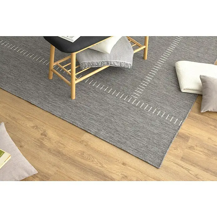 Alfombra exterior reversible In/Out Pespunte - Silver, 230 x 160 cm, Polipropileno - Primer plano de una elegante alfombra gris con un patrón lineal sobre un suelo de madera clara, creando un ambiente moderno y acogedor.