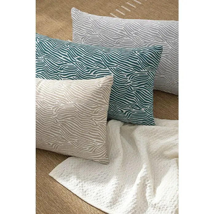 Cojín Jacquard Cebra - 50 x 30 cm, Textil, Taupe, Rectangular - Cojines decorativos en beige, verde azulado y gris con un patrón ondulado sobre una alfombra.