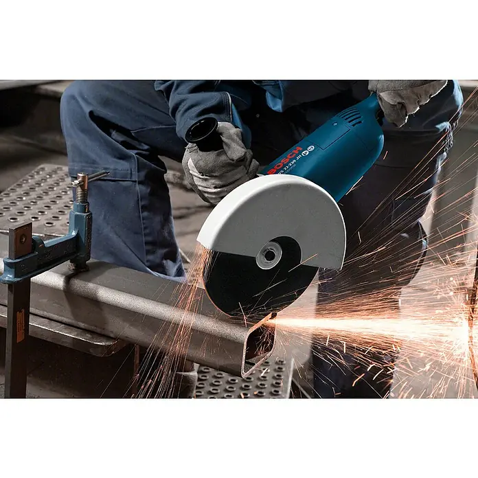 Bosch Professional Elektro-Winkelschleifer GWS 22-230 J - 2.200 W, Durchmesser Scheibe: 230 mm, Leerlaufdrehzahl: 6.500 U/min - Ein blauer Bosch Winkelschleifer schneidet durch ein Metallrohr, wobei helle Funken sprühen. Das Werkstück ist mit einer Schraubzwinge befestigt.