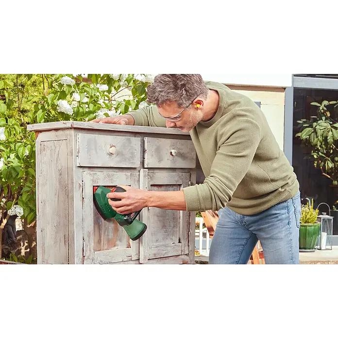 Bosch Power for All 18V Akku-Deltaschleifer Universal Sander 18V-10 - 18 V, Ohne Akku, Leerlaufschwingzahl: 12.000 U/min - 22.000 U/min - Ein Mann verwendet einen Bosch Exzenterschleifer, um ein antikes Sideboard aufzuarbeiten, wobei er Wert auf Heimwerkerprojekte legt.