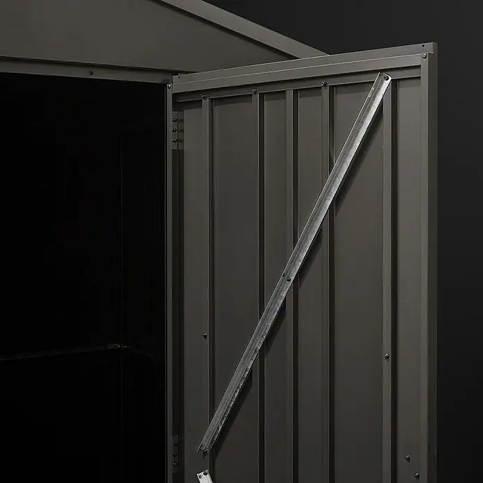Hoggar Gerätehaus Pioneer Y30 - Außenmaß inkl. Dachüberstand (B x T): 162 x 174 cm, Anthrazit, Stahl, 2,82 m² - Nahaufnahme des offenen Eingangs zu einem Geräteschuppen mit einer Metalltür und einer Stützstrebe. Der Schuppen ist dunkelgrau und steht vor einem schwarzen Hintergrund.