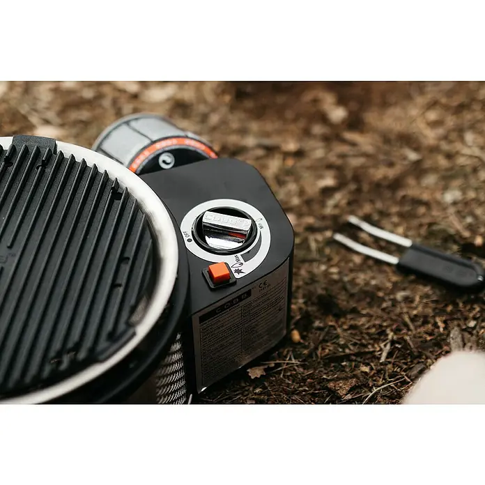Cobb Gasgrill Premier Gas Deluxe 2.0 - Durchmesser Grillfläche: 32 cm, 1,23 kW, Anzahl Brenner: 1 - Nahaufnahme eines Cobb-Grills auf dem Boden, mit Fokus auf Grillrost, Bedienfeld und Zubehör.