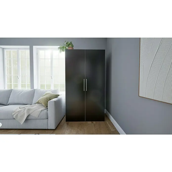 Respekta Schrankküche Peter - Breite: 104 cm, Schwarz/Weiß, Mit Duo-Kochmulde und Mikrowelle - Ein moderner Kleiderschrank in dunklem Holz mit silbernen Griffen, neben einem Sofa und unter einer Pflanze in einem hellen, modernen Raum.
