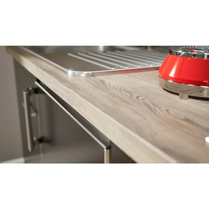Respekta Singleküche Luis - Breite: 150 cm, Schwarz, Mit Duo-Kochmulde, Farbe Arbeitsplatte: Eiche York - Detailaufnahme einer Küchenarbeitsplatte in Holzoptik mit Spülbecken, Abtropfgestell und rotem Küchengerät. Moderne und stilvolle Küchenausstattung.