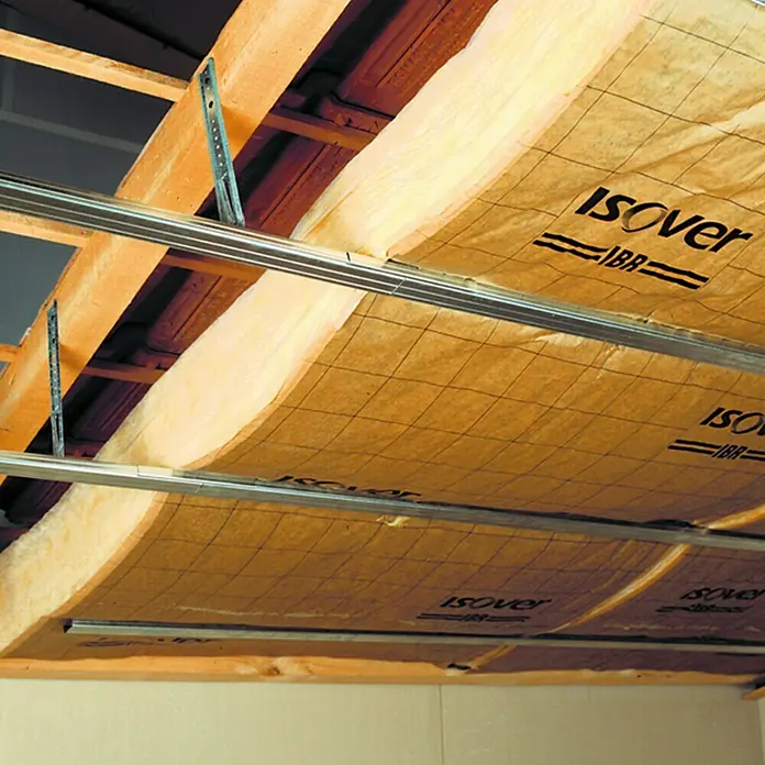 Isover Lana de vidrio IBR - L x An x Es: 12 m x 1,2 m x 80 mm - Primer plano del aislamiento de techo con paneles Isover, instalados entre vigas de madera y perfiles metálicos para eficiencia térmica.\n