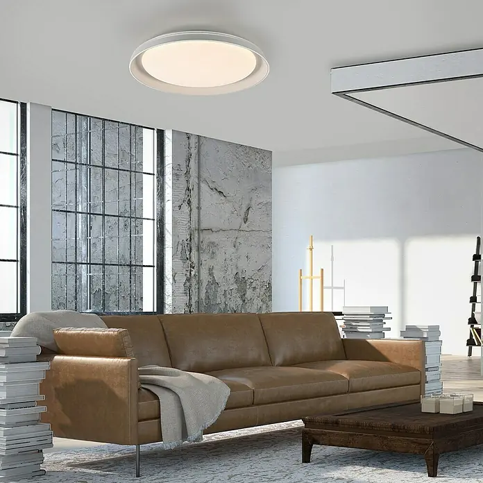 Paul Neuhaus LED-Deckenleuchte rund Sati - 23,5 W, Ø x H: 43 x 8,5 cm, Weiß, Warmweiß - Eine moderne, runde Deckenleuchte in Weiß spendet sanftes Licht in einem stilvollen Wohnzimmer mit Ledersofa und industriellem Akzent.