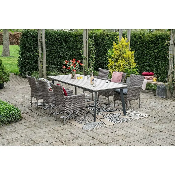 Garden Impressions Gartentisch Vigo - L x B x H: 230 x 100 x 73 cm, Aluminium, Vironwood, Rechteckig, Schwarz/Weiß - Eine Outdoor-Essgruppe mit hellem Holztisch und grauen Korbstühlen auf einer Terrasse mit gemustertem Teppich, bereit für ein Essen.