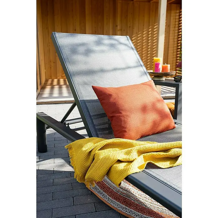 Garden Impressions Gartenliege - B x T x H: 72 x 200 x 32,5 cm, Aluminium, Schwarz/Anthrazit - Dunkelgraue Sonnenliege mit orangefarbenem Kissen und gelber Decke auf einer Terrasse, bereit zur Entspannung.