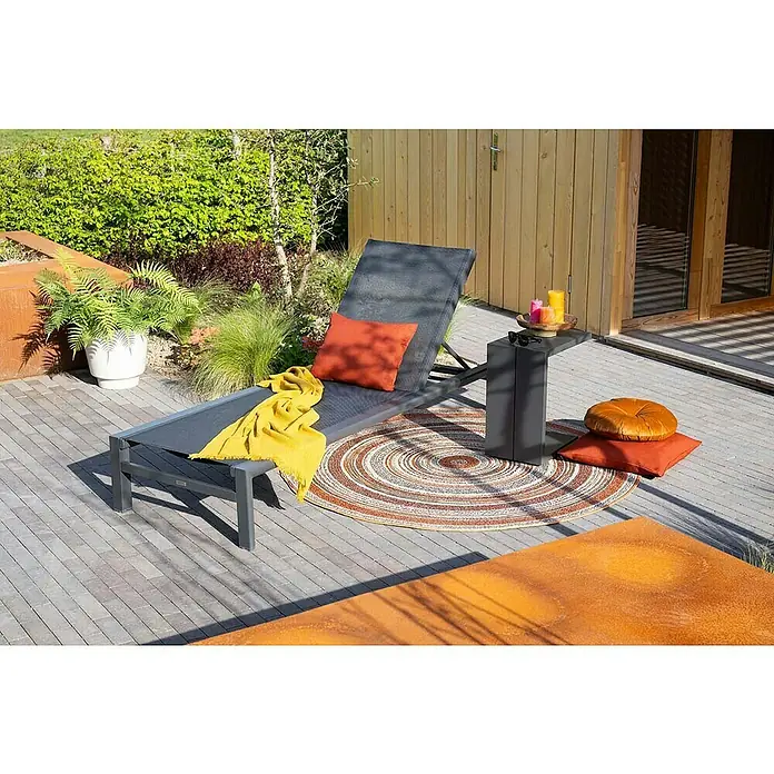 Garden Impressions Gartenliege - B x T x H: 72 x 200 x 32,5 cm, Aluminium, Schwarz/Anthrazit - Eine dunkelgraue Sonnenliege mit orangefarbenem Kissen und gelbem Plaid auf einer Terrasse, bereit zur Entspannung.
