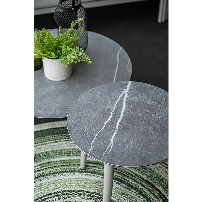 Garden Impressions Loungemöbel-Set Frigole - 5 -tlg., Aluminium, Taupe/Sand - Zwei runde Satztische mit grauer Marmor-Optik-Platte und hellen Beinen, auf einem grün-weiß gestreiften Teppich arrangiert.