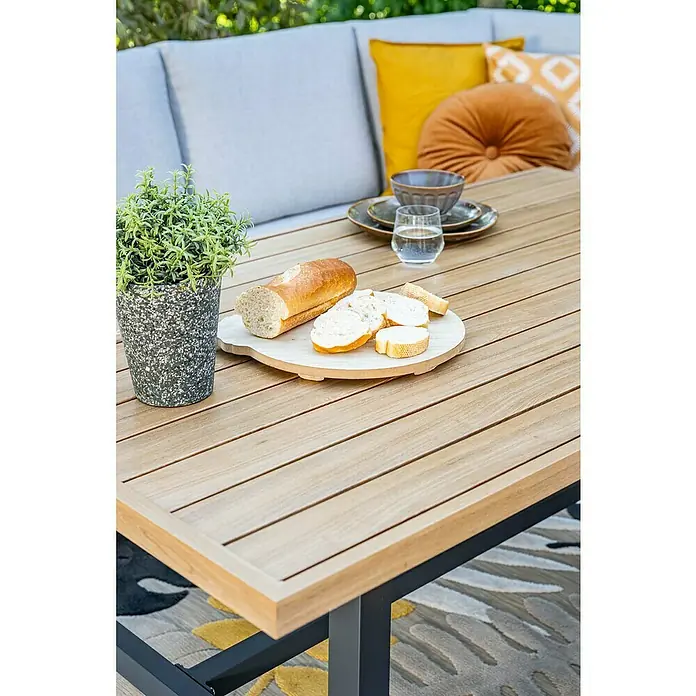 Garden Impressions Loungemöbel-Set Elati -  - Heller Outdoor-Tisch aus Holzlatten mit dunklen Metallbeinen, auf einer Terrasse mit Sofa, Brot und Pflanze für Mahlzeiten im Freien.