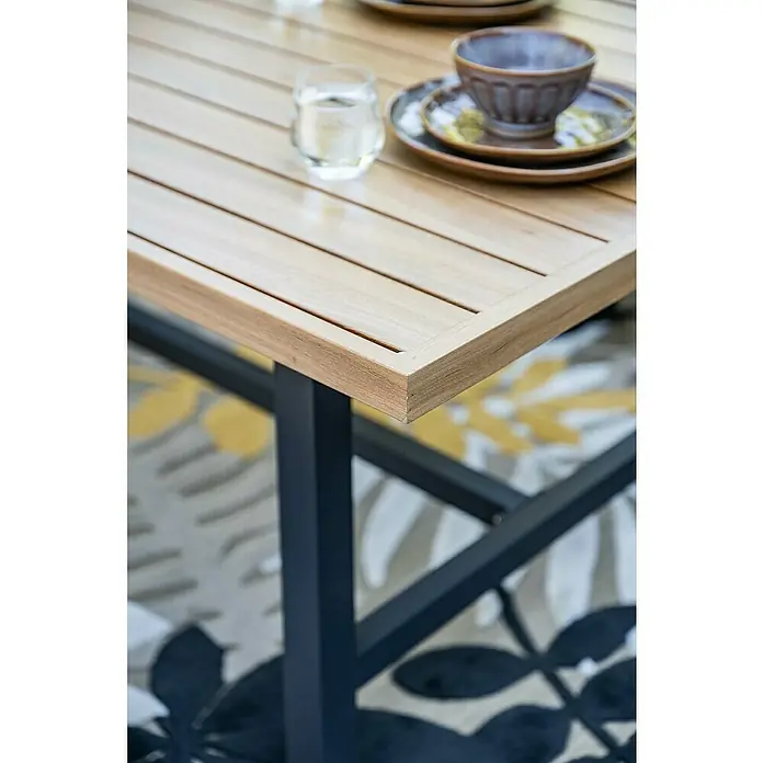 Garden Impressions Loungemöbel-Set Elati -  - Heller Holztisch mit Lattenplatte und dunklen Metallbeinen, gedeckt mit Geschirr und Wasserglas.