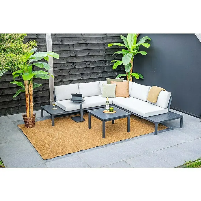 Garden Impressions Loungemöbel-Set Prinos - 4 -tlg., Aluminium, Grau/Schwarz - Dunkelgraue Outdoor-Eckloungegruppe mit hellgrauen Kissen, Beistelltisch und Couchtisch auf einem Terrassenteppich, umgeben von Pflanzen.