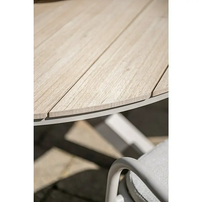 Garden Impressions Gartentisch rund Edison - Ø x H: 148 x 75 cm, Aluminium, Vironwood, Taupe - Nahaufnahme eines runden Gartentisches mit hellen Holzoptik-Latten und grauem Metallrahmen, daneben ein hellgrauer Stuhlarm.