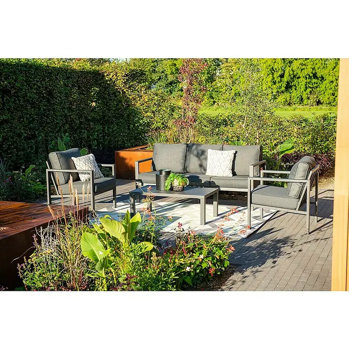 Garden Impressions Loungemöbel-Set Springs - 4 -tlg., Aluminium, Grau/Schwarz - Graues Lounge-Set aus Metall für den Außenbereich mit Sofa, zwei Sesseln und Couchtisch, auf einem Terrassenteppich inmitten üppiger Gartenpflanzen.