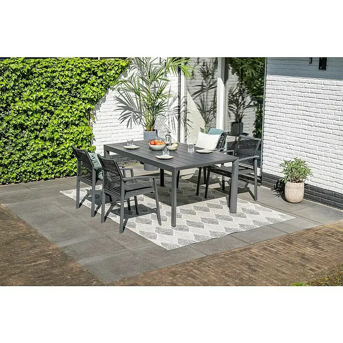 Garden Impressions Gartentisch Gosford - L x B x H: 180 x 100 x 74,6 cm, Aluminium, Rechteckig, Schwarz/Anthrazit - Ein dunkelgrauer Outdoor-Esstisch mit vier passenden Stühlen, auf einem gemusterten Teppich auf einer Terrasse für eine Mahlzeit bereitgestellt.