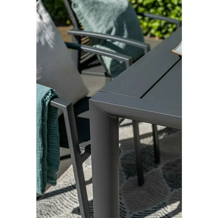 Garden Impressions Gartentisch Gosford - L x B x H: 180 x 100 x 74,6 cm, Aluminium, Rechteckig, Schwarz/Anthrazit - Dunkelgraue Outdoor-Sitzgruppe aus Metall mit Kissen und Decke auf einem Terrassenteppich.