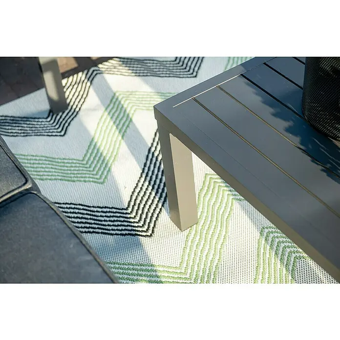Garden Impressions Loungemöbel-Set Springs - 4 -tlg., Aluminium, Grau/Schwarz - Anthrazitfarbener Lamellen-Outdoor-Tisch auf weißem Teppich mit grünen und schwarzen Zickzackmustern, dazu ein graues Kissen.
