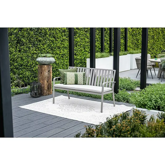 Garden Impressions Gartenbank Pisa - B x T x H: 150 x 52,5 x 89,5 cm, Aluminium, Polyester, Taupe - Graue Gartenbank mit hellen Kissen und gemustertem weißem Outdoor-Teppich auf einer Terrasse.